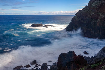 Scenic view of rocks in sea against sky