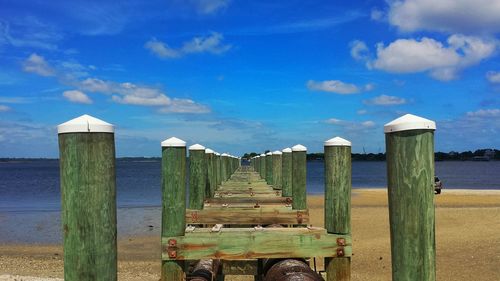 Wooden pier on sea against cloudy sky