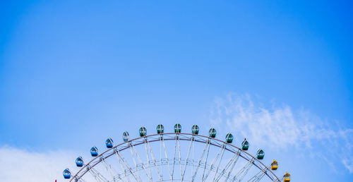 Low angle view of ferris wheel against blue sky