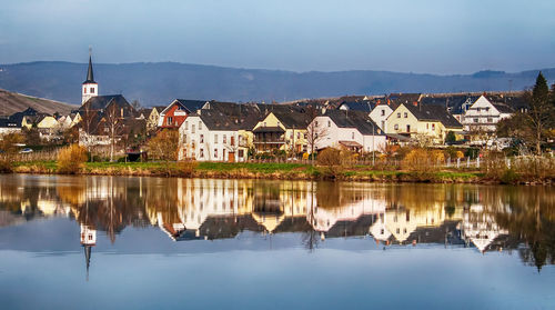 Scenic view of lake by houses against sky