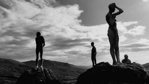 People standing on rock against sky