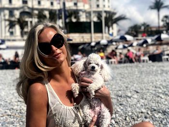 Portrait of smiling woman holding dog at beach