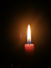 Close-up of lit candle against black background