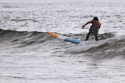 Rear view of man surfing in sea