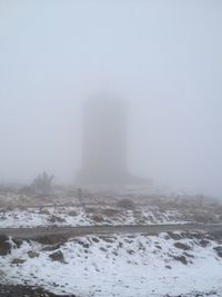 Frozen landscape against sky during foggy weather
