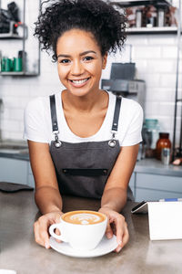 Portrait of smiling young woman sitting on table