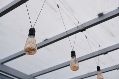Low angle view of light bulbs hanging from ceiling