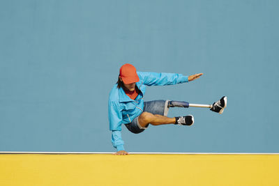 Full length of man skateboarding on wall against blue sky