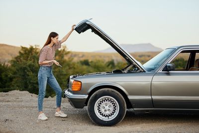 Side view of young woman holding car