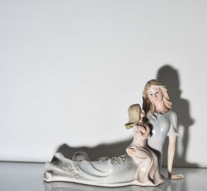 Female sculpture on table against white background