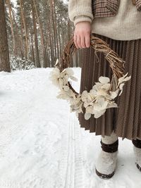 Low section of woman holding snow on plant