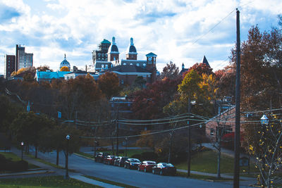 Cars on street amidst buildings against sky in city