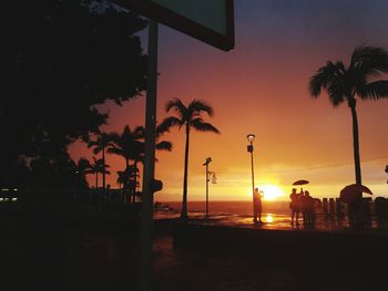 Silhouette palm trees on beach against sky during sunset