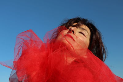 Low angle view of woman with eyes closed against clear blue sky
