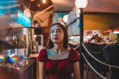 Portrait of young woman standing against illuminated lights