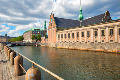 Bridge over river by buildings against sky