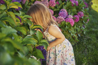 Adorable child dressed as a butterfly smelling flowers