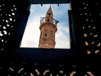 Low angle view of cross by building against sky