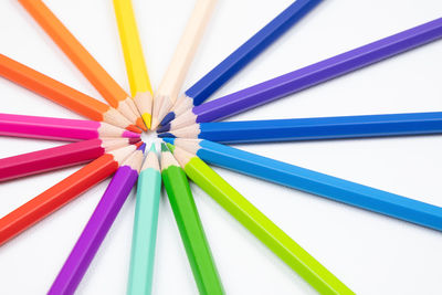 High angle view of multi colored pencils over white background