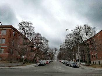 Cars on street by buildings in city against sky