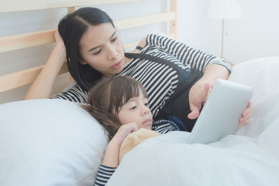 Woman using mobile phone on bed