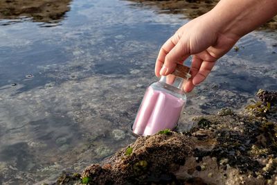 High angle view of hand holding bottle by lake