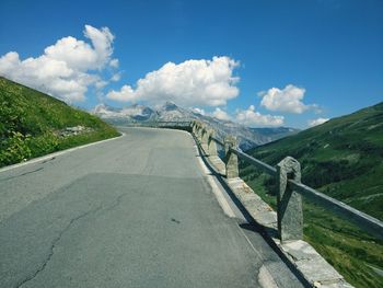 Empty road leading towards mountains against sky