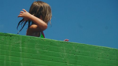 Side view of woman on green landscape against blue sky