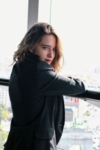 Side view portrait of young woman standing by window