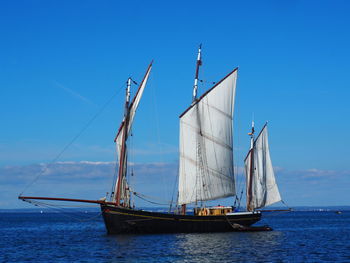 Sailboat sailing on sea against blue sky