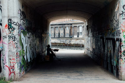 Silhouette street musician sitting in tunnel