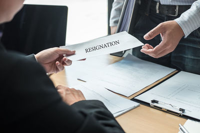 Midsection of man holding paper with text on table