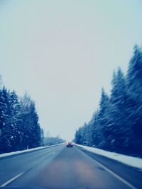 Road in forest against clear sky during winter