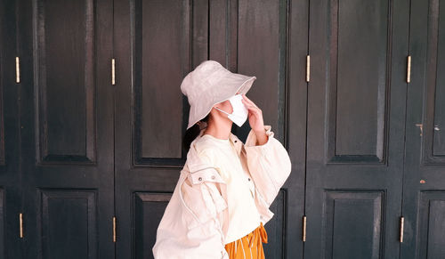 Side profile of an asian woman portrait, wearing a white mask and a sun hat