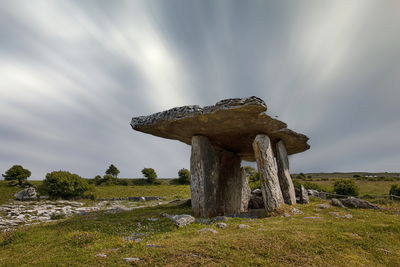 Poulnabrone dolmen on landscape against cloudy sky at clare, ireland
