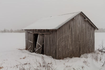 House on snow covered field against sky