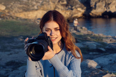 Portrait of young woman photographing outdoors