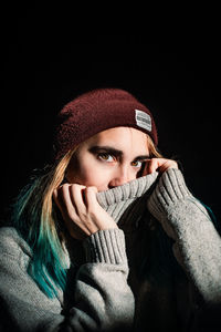 Portrait of beautiful woman covering face against black background