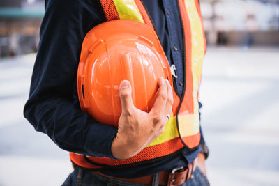 Midsection of man holding hardhat