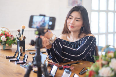 Young woman using phone while standing on table