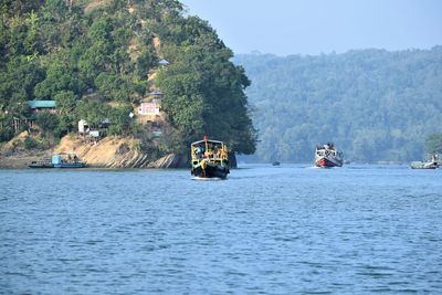 Boat sailing on river by tree mountain