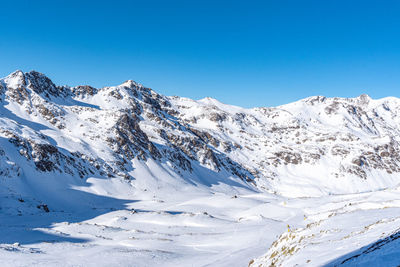 Scenic view of snowcapped mountains against clear blue sky