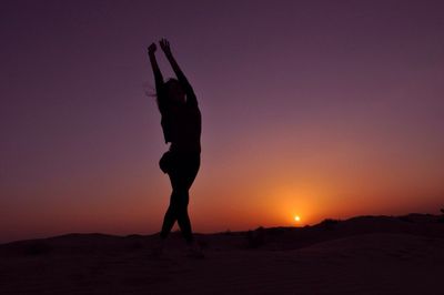 Silhouette of woman standing at sunset