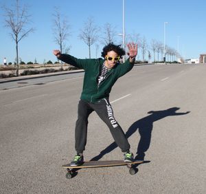 Young man skateboarding on road in city