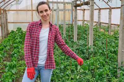 Young woman standing against plants