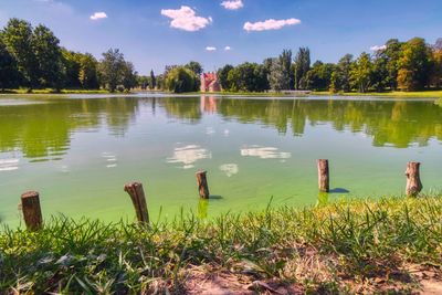 Scenic view of wooden posts in lake against sky