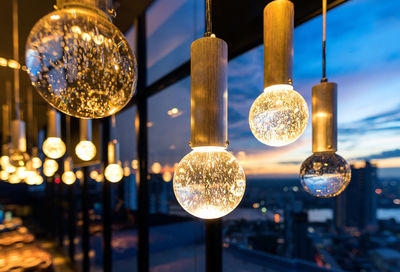 Close-up of illuminated light bulb hanging at night