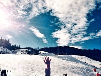 Person hand on snowcapped mountain against sky