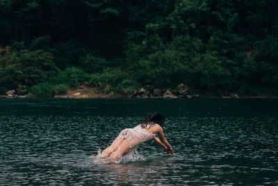 Man surfing in lake against trees