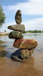 Stack of stones on rock at beach against sky